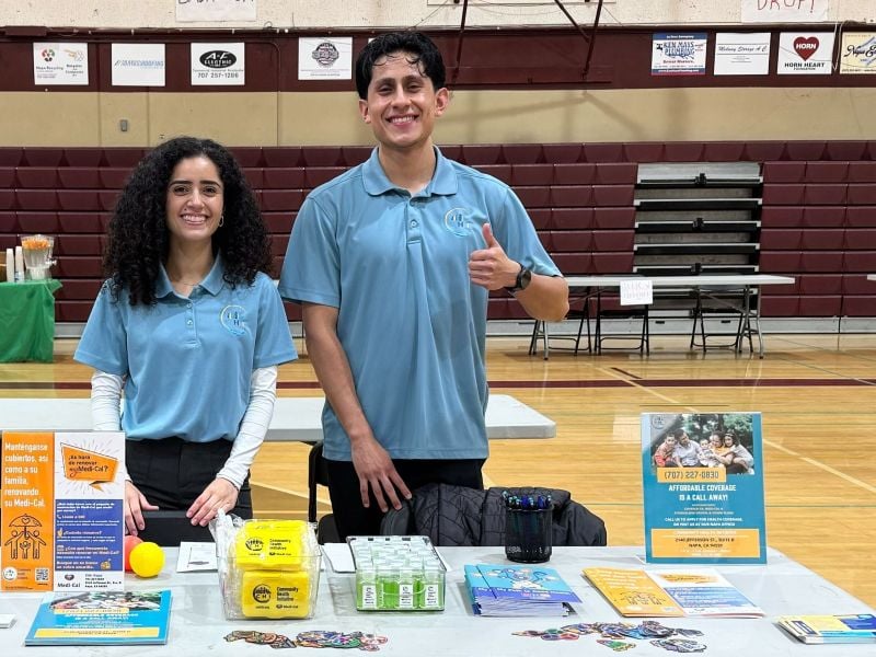 Two people at informational booth in gymnasium.