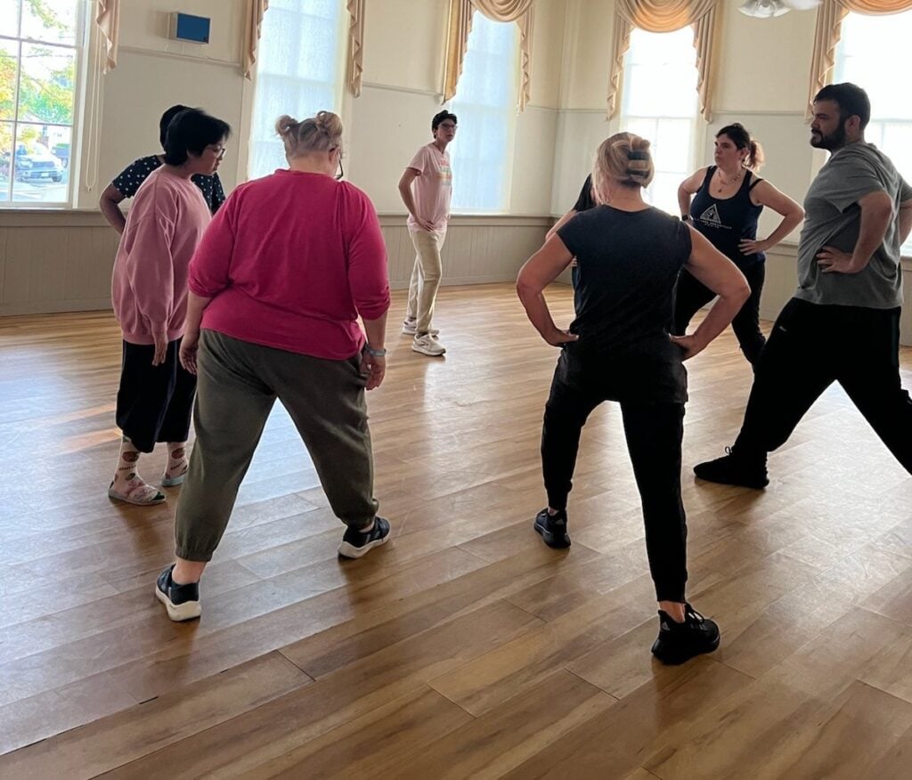 Group dance class in a bright studio room.
