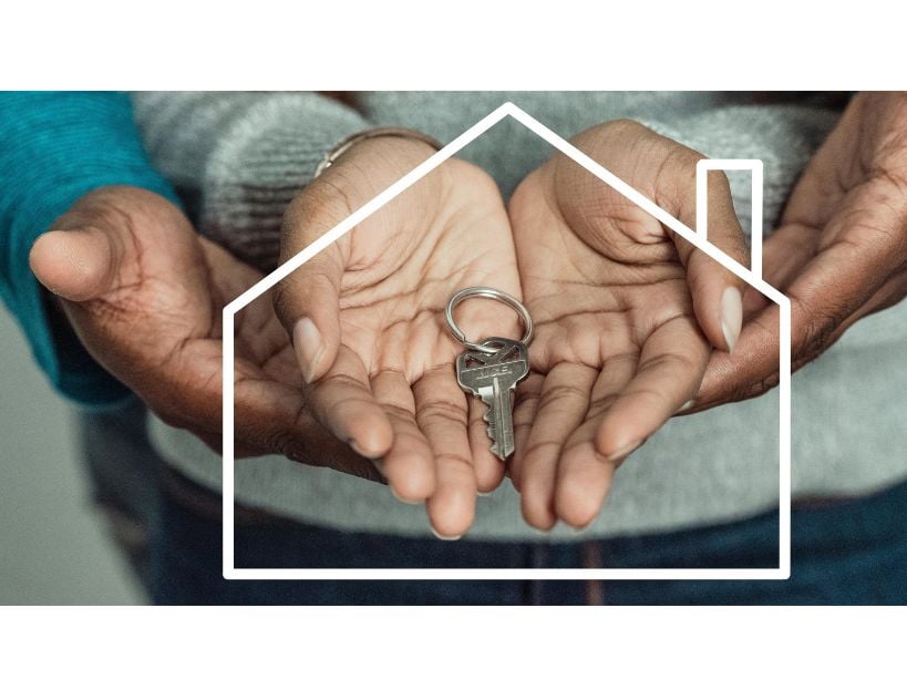 Hands holding house key, symbolizing home ownership.