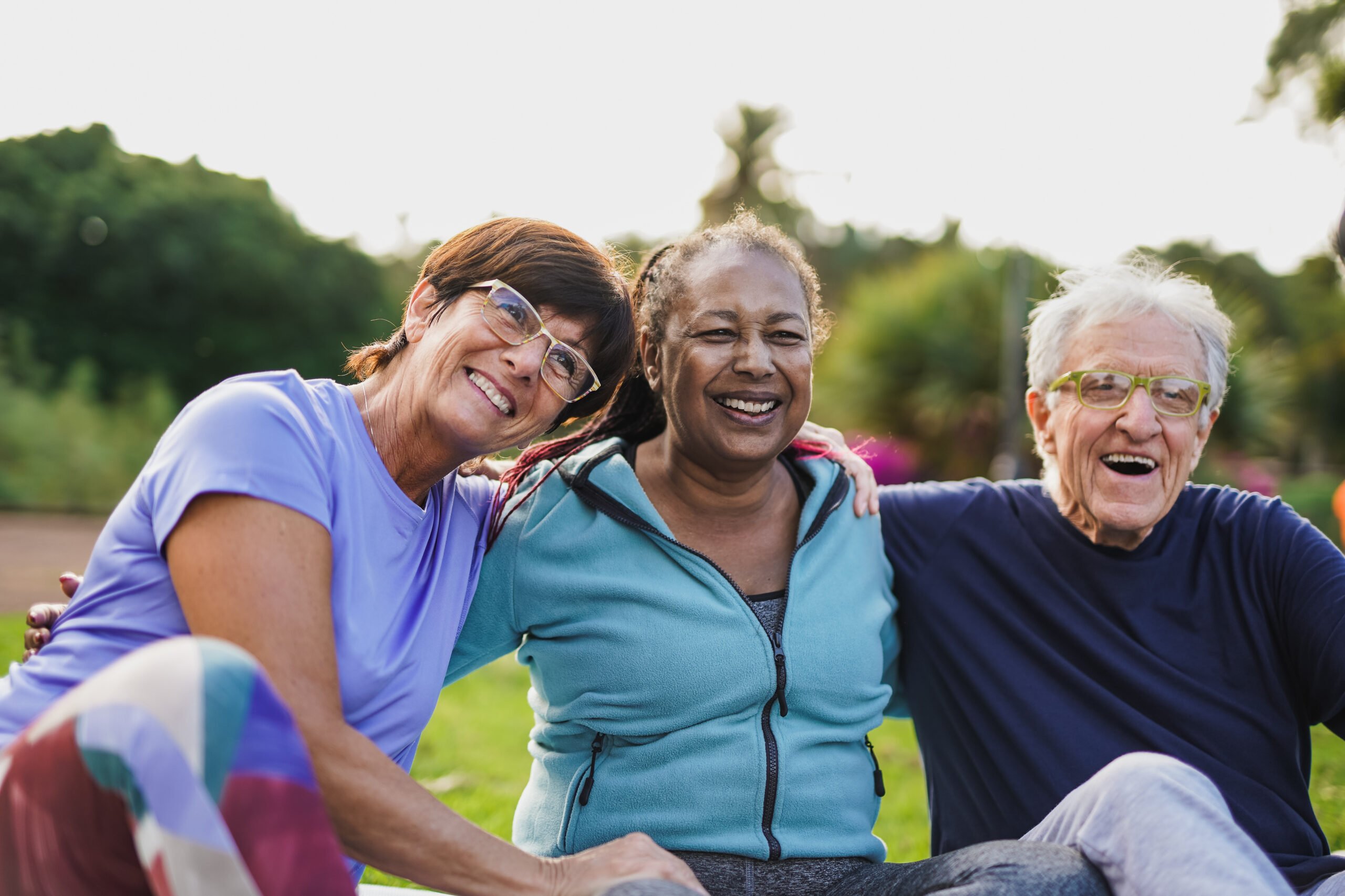 Three happy seniors sitting in a park.