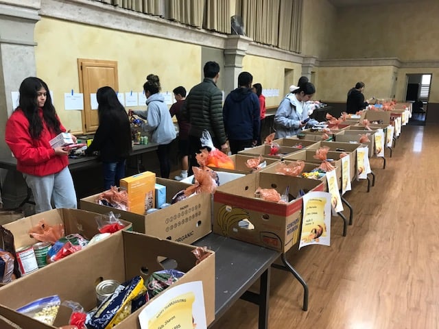 Volunteers sorting donations in large boxes indoors.