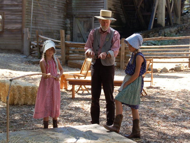Man teaching kids traditional farming techniques.