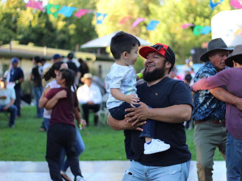 Man holding smiling child at outdoor event