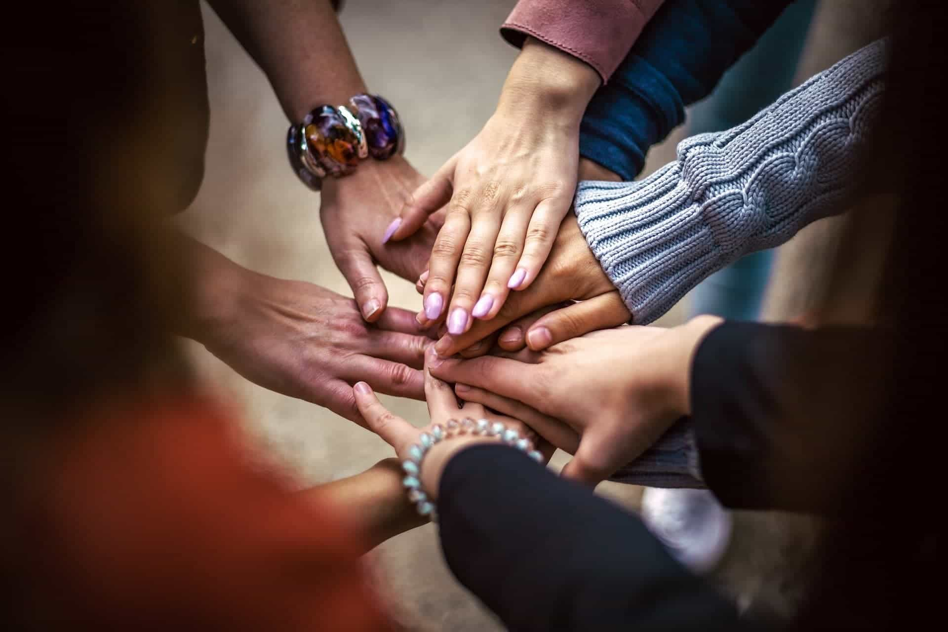 different races put hands down in team work symbol