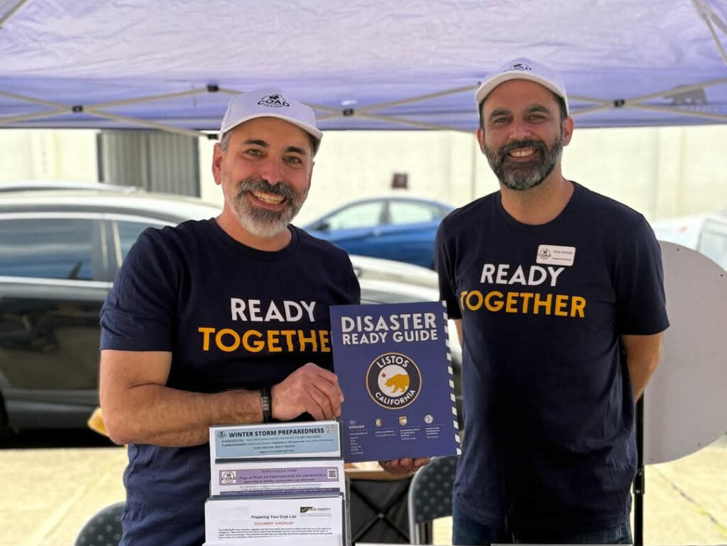 Two men promoting disaster preparedness guide at an event.