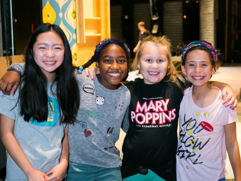 Smiling children in theater setting.