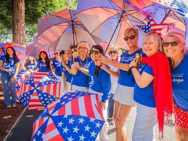 Women with American flag umbrellas and blue shirts.