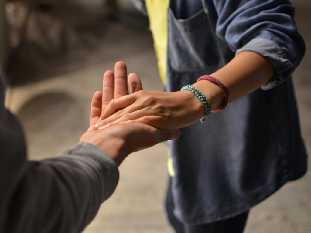 Two people holding hands and offering support.
