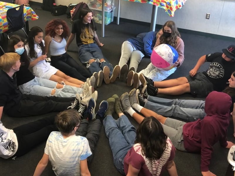 Teen group seated in circle with beach ball.